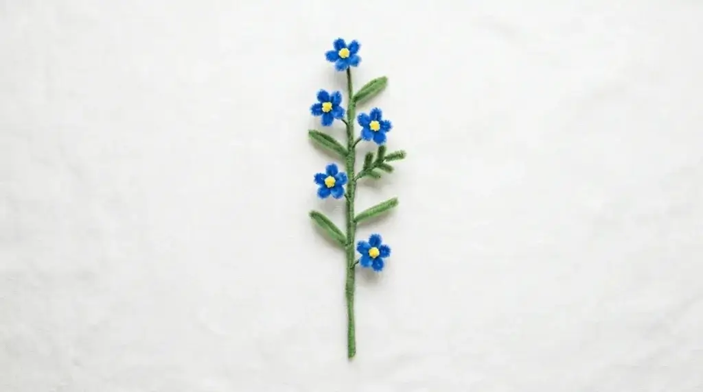 Complete pipe cleaner forget-me-not spray with 5 blue flowers attached at intervals along a single green stem
