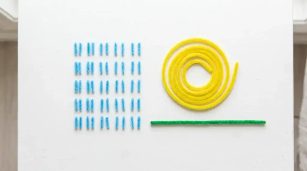 Materials needed for pipe cleaner forget-me-nots — sky blue pipe cleaner cut into small pieces, yellow pipe cleaner and green stem on white surface