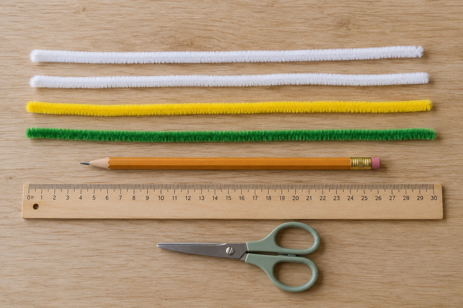 Two white, one yellow, and one green pipe cleaner with a pencil, ruler, and scissors on a wooden table
